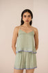 Woman wearing a green patterned top and shorts set on a beige background Calling June
