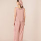 Woman wearing a pink textured jumpsuit with a matching headscarf on a beige background Calling June