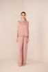 Woman wearing a pink textured sleeveless top and pants on a beige background Calling June